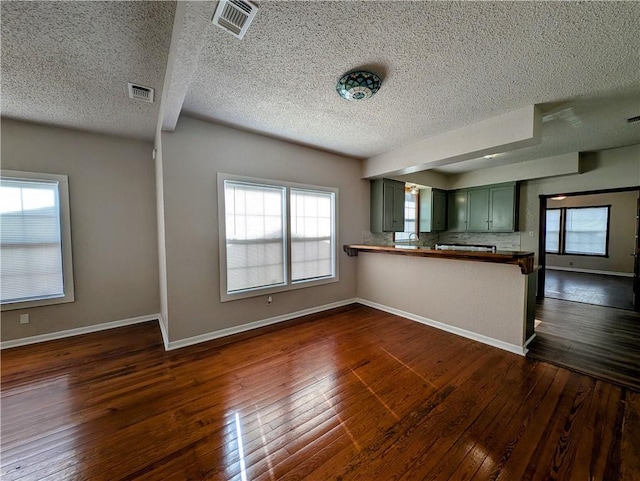 kitchen featuring baseboards, visible vents, dark wood-type flooring, and green cabinetry