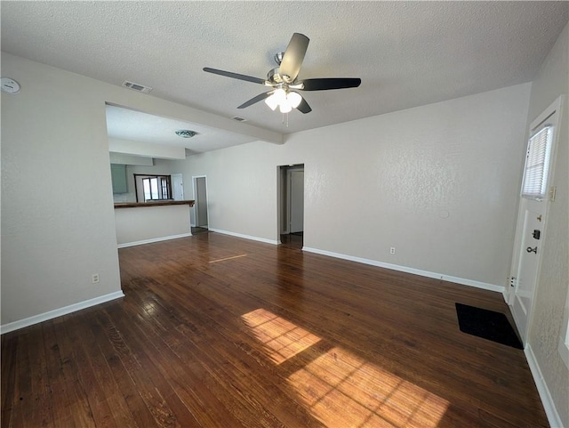 spare room with a textured ceiling, hardwood / wood-style flooring, visible vents, and baseboards