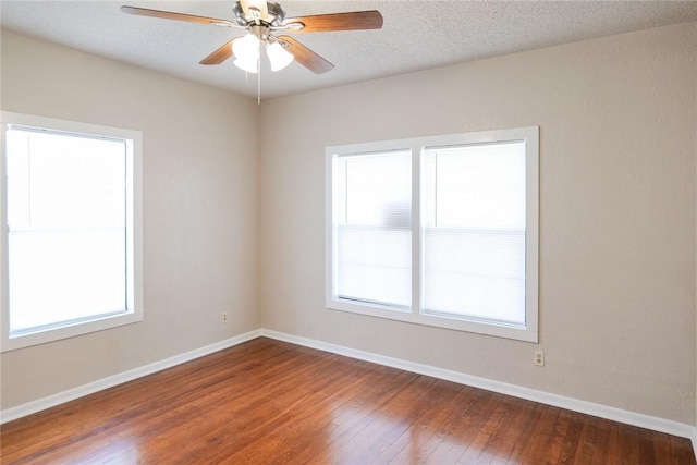 empty room featuring dark wood-style floors, plenty of natural light, and baseboards