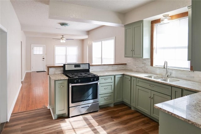 kitchen featuring green cabinetry, a sink, a peninsula, and gas range