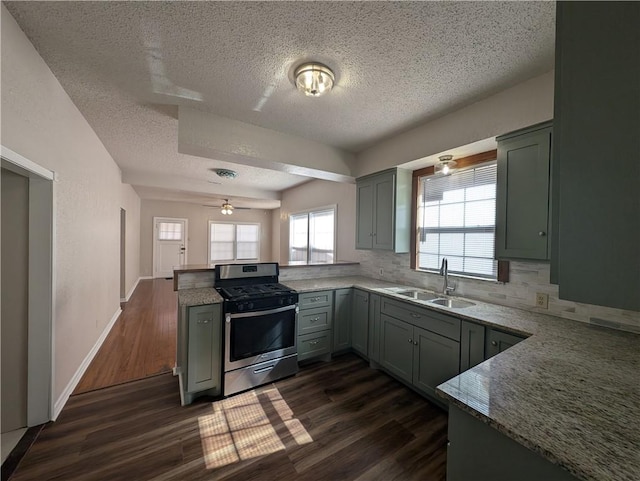 kitchen with stainless steel range with gas cooktop, dark wood finished floors, gray cabinets, a sink, and a peninsula