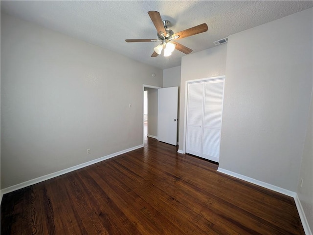 unfurnished bedroom featuring baseboards, visible vents, dark wood-style floors, ceiling fan, and a closet