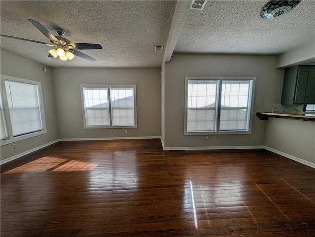 unfurnished living room featuring visible vents, dark wood finished floors, baseboards, and ceiling fan