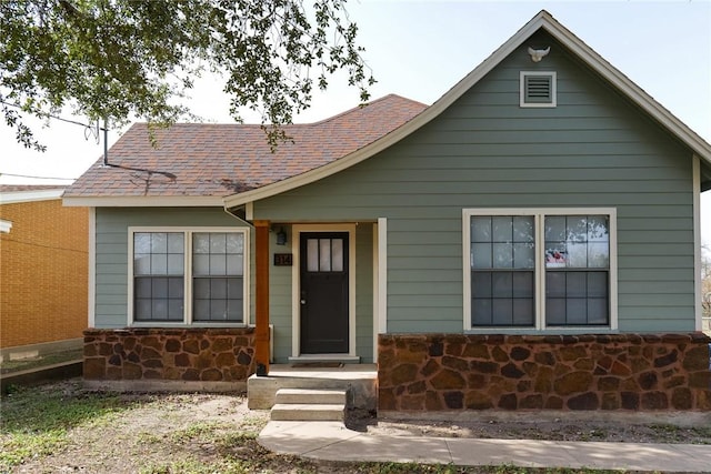 view of front of house with stone siding and a shingled roof