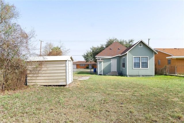 back of house featuring a yard, a storage unit, entry steps, fence, and an outdoor structure