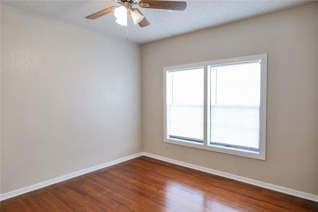 spare room featuring a textured ceiling, dark wood finished floors, and baseboards