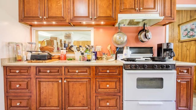 kitchen featuring white range with gas stovetop and wooden walls