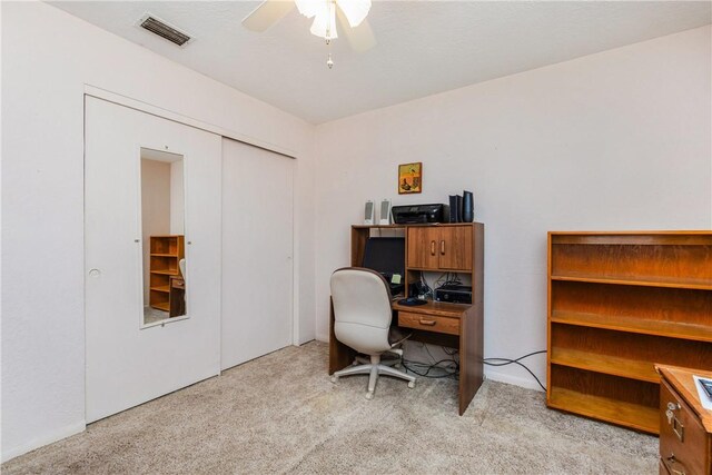 office area with a ceiling fan, light colored carpet, and visible vents