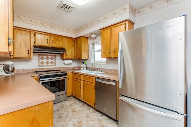 kitchen with visible vents, under cabinet range hood, a sink, appliances with stainless steel finishes, and light countertops