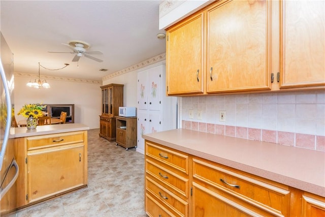 kitchen with tasteful backsplash, white microwave, ceiling fan with notable chandelier, and light countertops