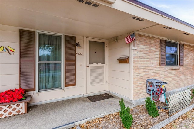 property entrance with visible vents and brick siding