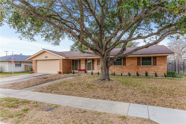 ranch-style home with fence, concrete driveway, a front lawn, a garage, and brick siding