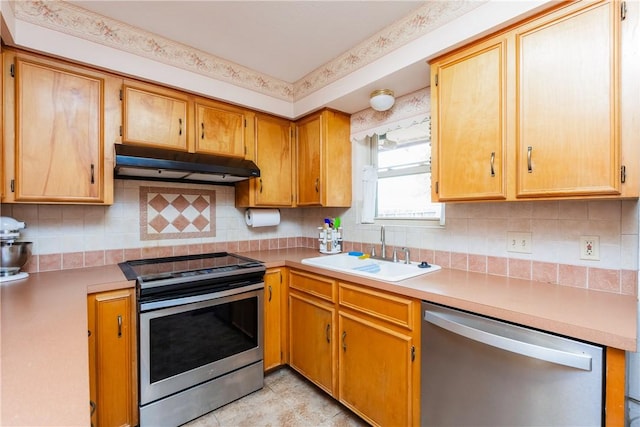 kitchen featuring under cabinet range hood, a sink, backsplash, appliances with stainless steel finishes, and light countertops