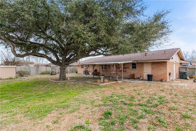 rear view of house with a patio, brick siding, a fenced backyard, and a lawn