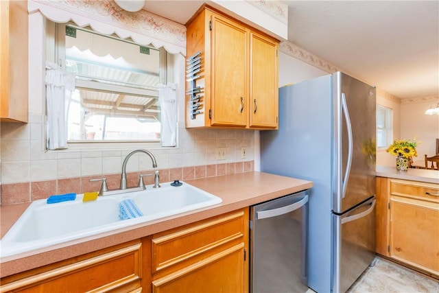 kitchen featuring tasteful backsplash, appliances with stainless steel finishes, light countertops, and a sink