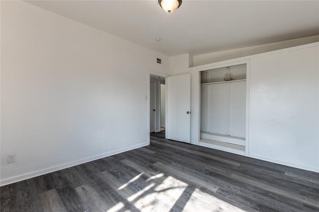 unfurnished bedroom with dark wood-type flooring and a closet