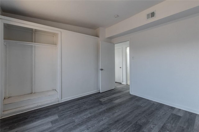 unfurnished bedroom with dark hardwood / wood-style flooring and a closet