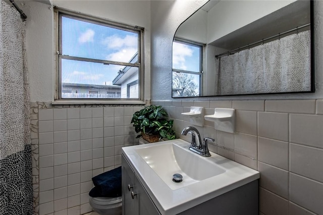 bathroom featuring vanity, toilet, and tile walls