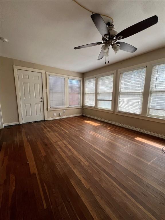 interior space with plenty of natural light, dark wood finished floors, a ceiling fan, and baseboards