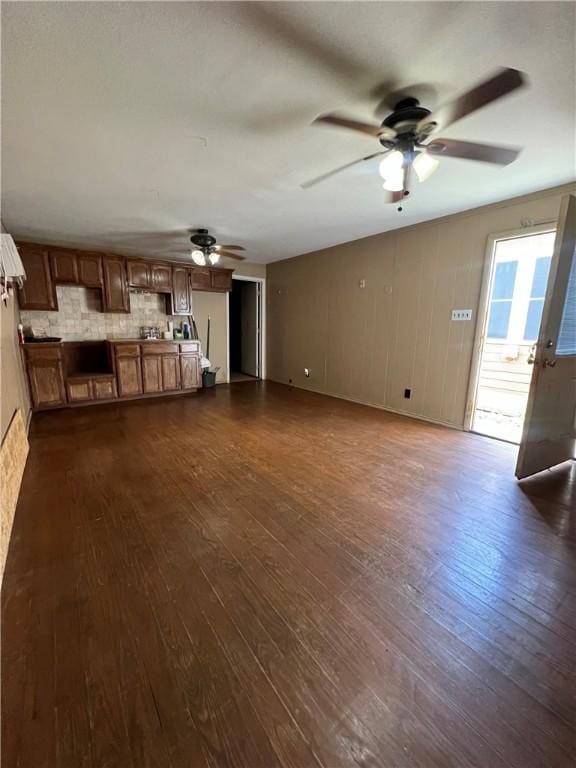 unfurnished living room featuring ceiling fan and dark wood-style flooring