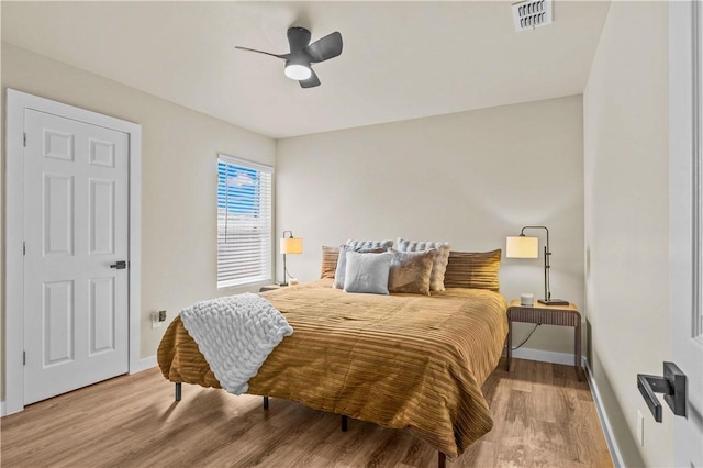 bedroom featuring ceiling fan, wood finished floors, visible vents, and baseboards