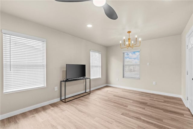 unfurnished living room featuring light wood-type flooring, recessed lighting, baseboards, and ceiling fan with notable chandelier