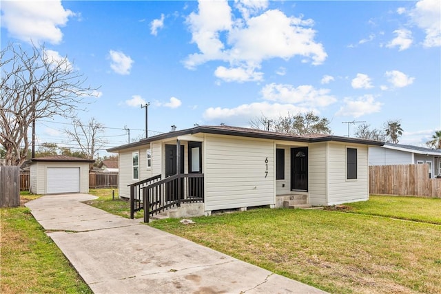 view of front of house featuring an outbuilding, a detached garage, entry steps, fence, and a front lawn