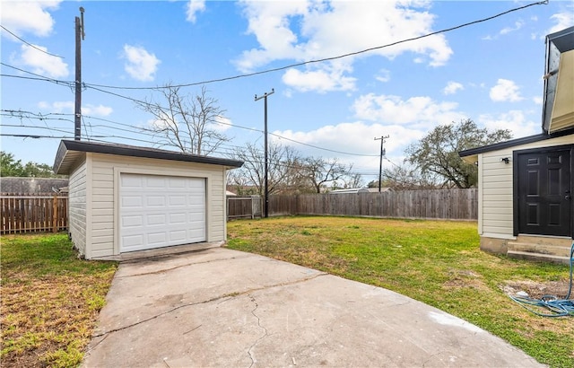 view of yard featuring an outbuilding, concrete driveway, entry steps, a garage, and a fenced backyard