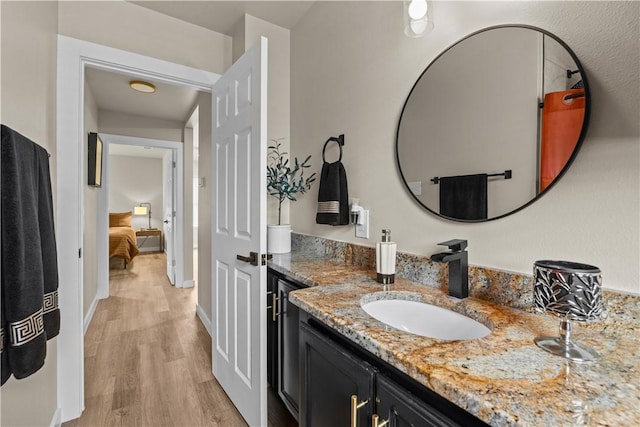 bathroom featuring baseboards, wood finished floors, and vanity