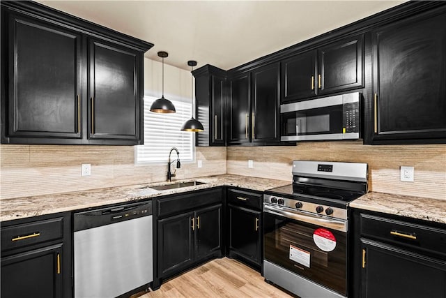 kitchen featuring stainless steel appliances, dark cabinetry, a sink, and decorative backsplash