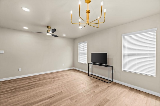 unfurnished living room featuring light wood-type flooring, ceiling fan with notable chandelier, baseboards, and recessed lighting