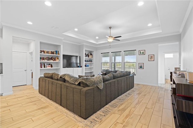 living room featuring crown molding, light hardwood / wood-style flooring, a raised ceiling, and ceiling fan