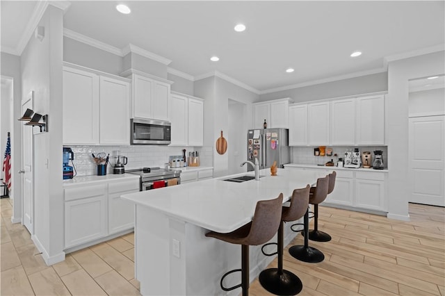 kitchen with white cabinetry, appliances with stainless steel finishes, a kitchen bar, and sink