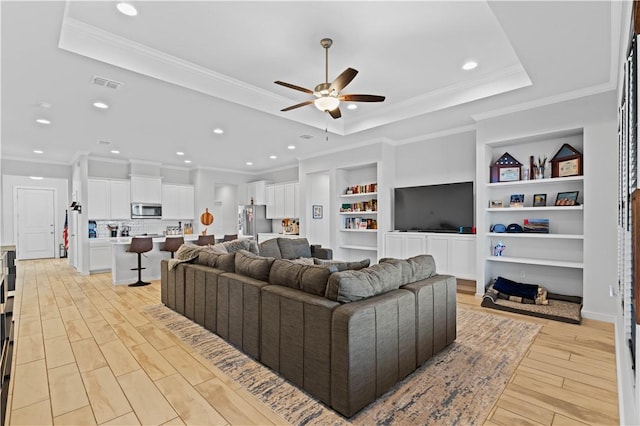 living room with crown molding, ceiling fan, a raised ceiling, and light hardwood / wood-style floors