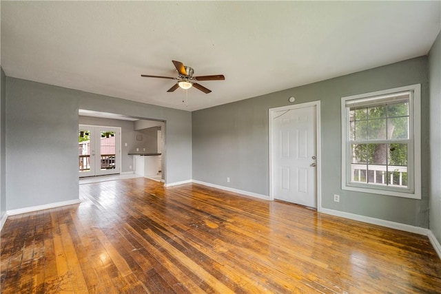 unfurnished living room with baseboards, ceiling fan, wood-type flooring, and french doors
