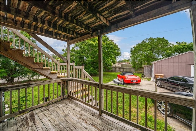 wooden terrace featuring a lawn, fence, and stairway