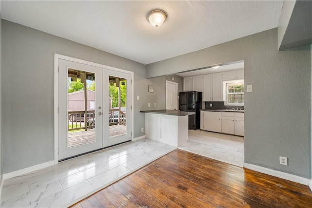 kitchen featuring dark countertops, baseboards, freestanding refrigerator, and french doors