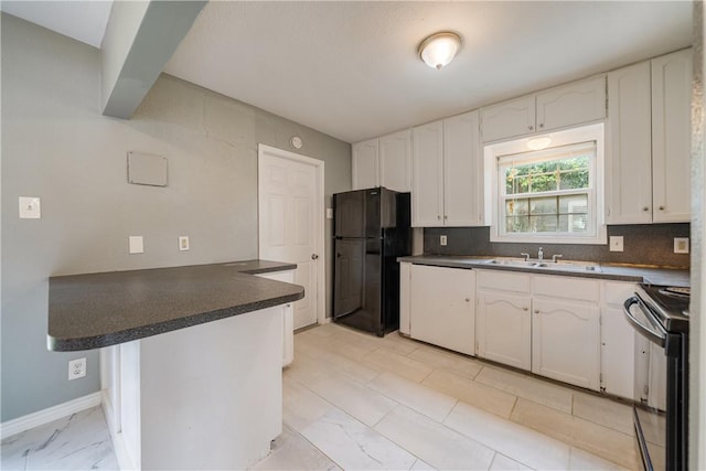 kitchen featuring dark countertops, a sink, black appliances, a peninsula, and white cabinetry