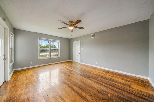 spare room with baseboards, ceiling fan, wood-type flooring, and visible vents