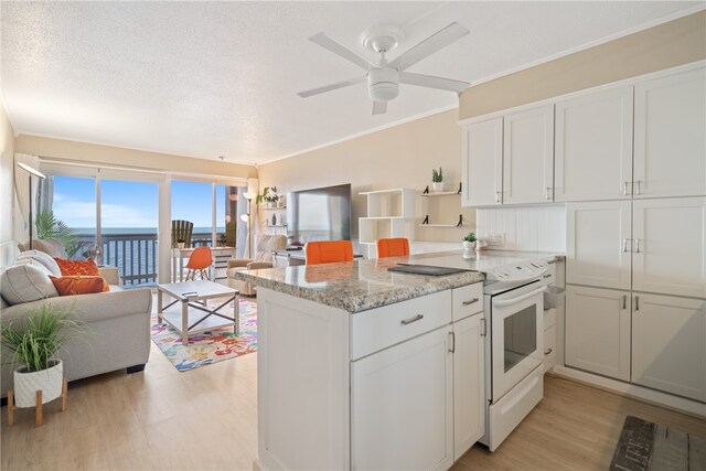 kitchen with white cabinets, white range with electric stovetop, light hardwood / wood-style floors, and light stone countertops