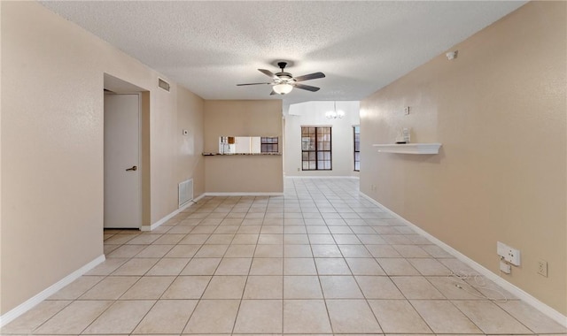 unfurnished room featuring a textured ceiling, light tile patterned floors, visible vents, and ceiling fan