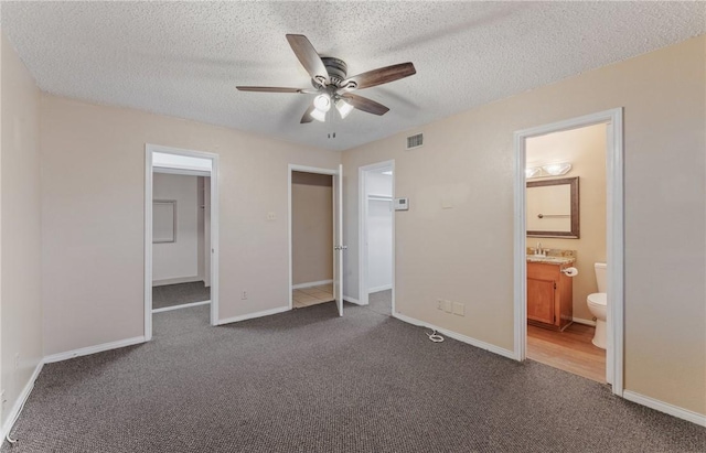 unfurnished bedroom featuring a spacious closet, visible vents, a closet, and carpet