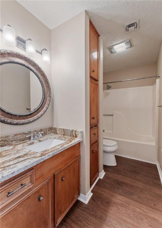 bathroom featuring vanity, wood finished floors, visible vents, a textured ceiling, and toilet