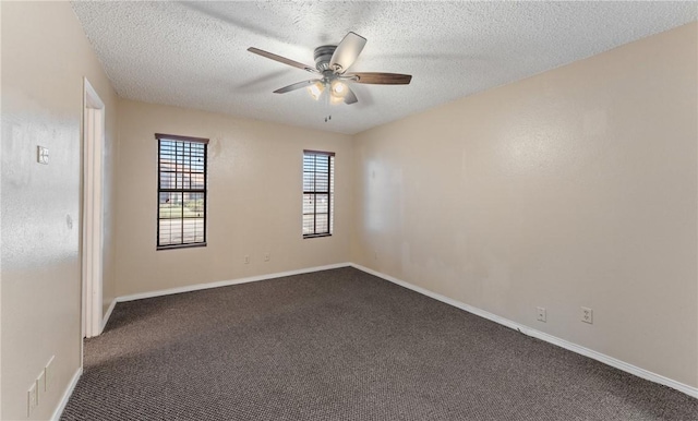 spare room with baseboards, dark carpet, a textured ceiling, and a ceiling fan