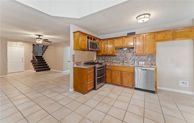 kitchen featuring a sink, stainless steel appliances, backsplash, and brown cabinetry