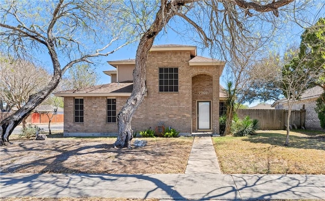 traditional-style house featuring brick siding, a front lawn, and fence