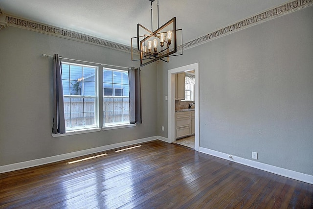 empty room featuring dark hardwood / wood-style floors, ornamental molding, and an inviting chandelier