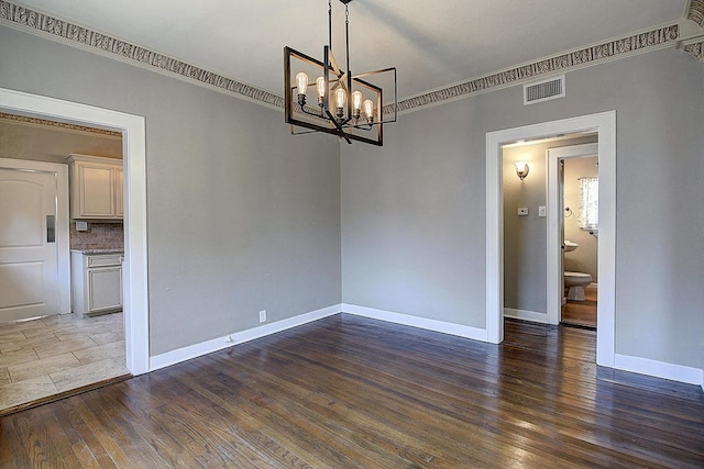 empty room featuring dark hardwood / wood-style flooring, a chandelier, and ornamental molding