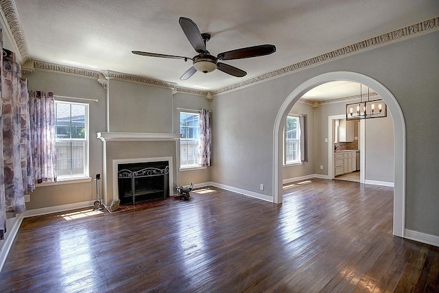 unfurnished living room with dark hardwood / wood-style floors, a healthy amount of sunlight, crown molding, and ceiling fan