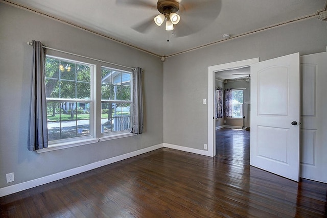 empty room with dark hardwood / wood-style floors, a healthy amount of sunlight, crown molding, and ceiling fan